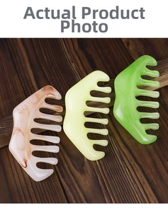 Three wide-tooth meridian massage combs in marbled, yellow, and green resin on wood