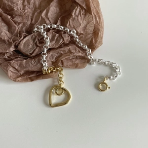 Detail of mixed-metal S925 silver and gold link bracelet with a heart pendant charm