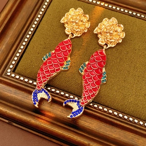 Macro detail of vintage gold koi fish earrings with red enamel and blue crystals in a frame