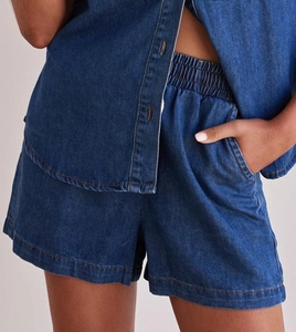 Detailed close-up of dark blue denim fabric texture and stitching on shirt and shorts set