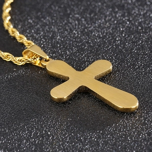 Macro shot of minimalist gold stainless steel cross pendant with matching link chain