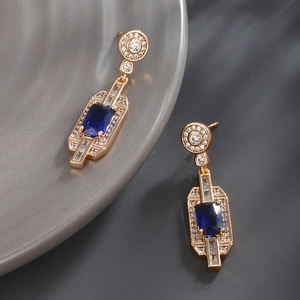 Close-up of vintage geometric gold earrings with rectangle blue stones and zircons