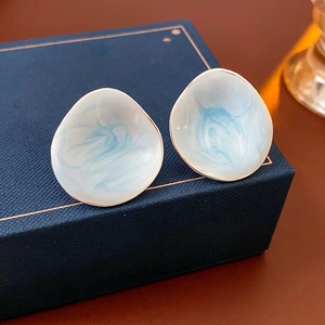 Dettaglio di orecchini vintage con perle marmorizzate e bordi dorati su scatola