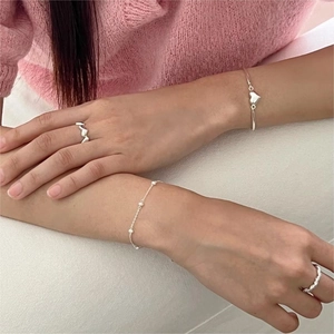 Silver minimalist heart ring and pearl bracelet set shown worn on a model hand