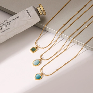 Detail view of heart, oval, and square blue cat's eye stone pendants on gold chains.