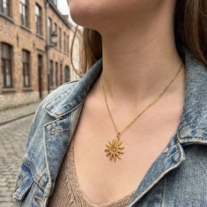 Elegant gold sun pendant necklace with spiral center on a fashion model in street setting