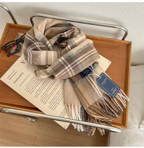 Classic British checkered scarf in beige and brown with elegant fringe on a wooden tray