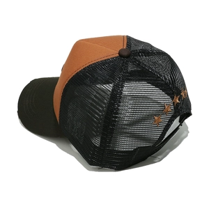Detail of five bronze-gold stars embroidered on the breathable mesh of a trucker cap
