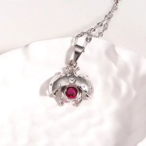 Detailed close-up of a silver ladybug pendant necklace with red and white gemstones
