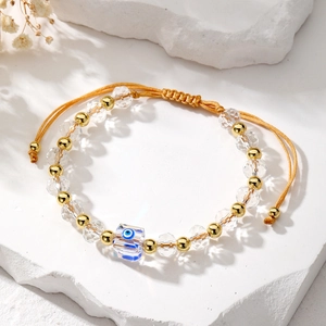 Detail of evil eye bracelet with faceted clear beads and golden adjustable woven cord