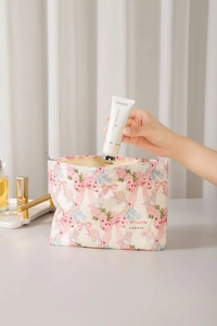 Detail of hand placing cream into the pink bow floral cotton makeup organizer bag