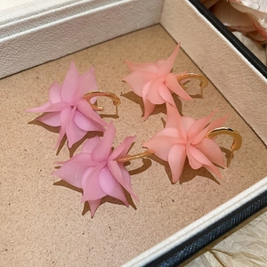 Detail of flower petal C-shape earrings in pastel purple and orange acrylic