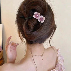 Detail shot of purple floral hair clip worn on a messy bun for an elegant daily look