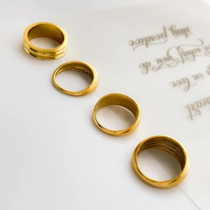 Close-up of four gold curved ring set featuring smooth, ribbed, and multi-layered textures