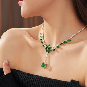 Detail of flower necklace with sparkling green zircon drop pendant on model neck