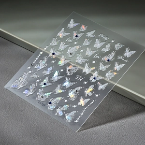Holographic butterfly nail stickers with rhinestones and cursive text on dark background