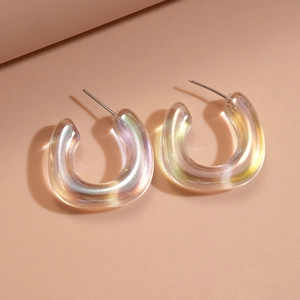 Macro detail of iridescent C-shaped acrylic earrings with subtle aurora finish and silver needles