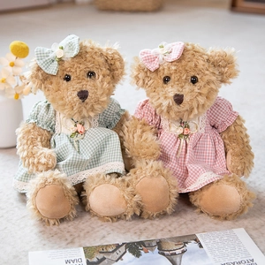 Matching pair of green and pink teddy bears wearing lace dresses and bows in home setting