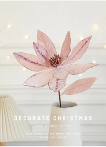 Pink velvet Christmas artificial flower with glitter in a white ceramic vase with warm lights