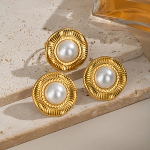 Gros plan d'un ensemble boucles d'oreilles et bague en perles dorées sur pierre texturée
