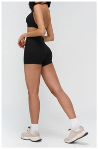 Detail of black backless yoga vest and high-waisted fitness shorts on a female model