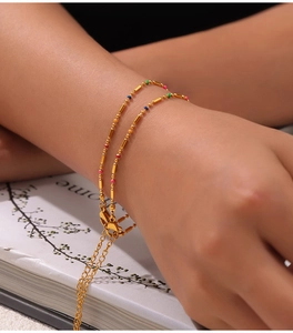Close-up of golden titanium steel bracelet with colorful beads and bow clasp detail