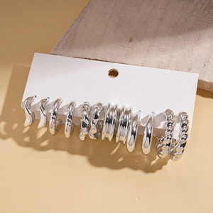Detailed view of silver hoop earring set with various textures on a white card display