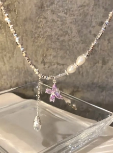 Primo piano di una collana con ciondolo a farfalla in zircone, perline d'argento e perle.