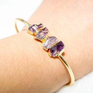 Macro detail of natural raw amethyst clusters set on a sleek gold-plated adjustable cuff