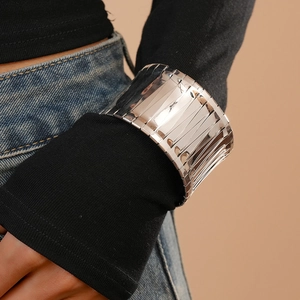 Detail of a wide silver irregular bangle with a polished mirror finish on the wrist