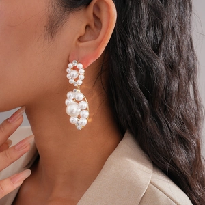 Close-up of cluster pearl earrings with zircons in gold setting on female model