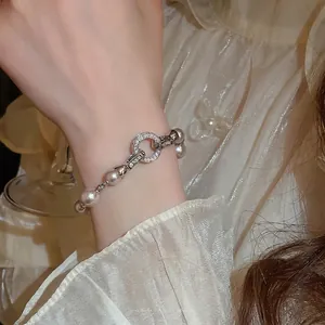 Bracelet en perles style français avec fermoir pavé de zircons porté par une femme