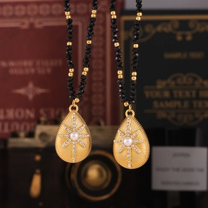 Eight-pointed star necklace with gold teardrop pendant and black faceted beads