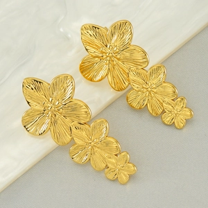 Detailed view of triple flower stud earrings with radiant metal textures and gold finish