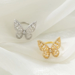 Close-up of gold and silver butterfly rings with sparkling zircon inlay on white soft gauze