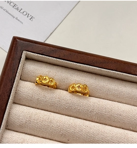 Detail showing gold-plated coin earrings on a beige linen jewelry box backdrop