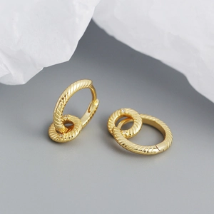 Detail of gold twisted hoop earrings with interlocking zircon-studded small rings