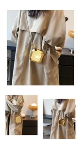 Detail view of the geometric gold acrylic box bag with sleek metal chain shoulder strap