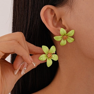 Minimalist green floral stud earrings with gold stamen worn by model for summer style