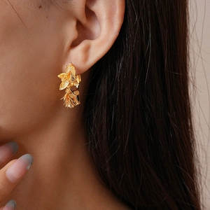 Gros plan de boucles d'oreilles pendantes en feuilles d'or portées par un mannequin
