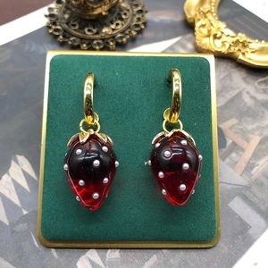 Elegant strawberry pearl earrings with 925 silver needles on a green velvet display