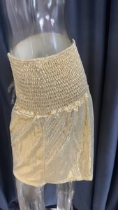 Detailed view of gold metallic high-waisted shorts with elastic pleated waistband texture