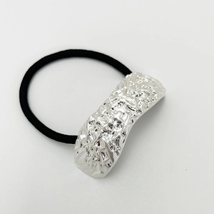 Detailed view of silver metallic ornament with irregular texture on black elastic hair tie