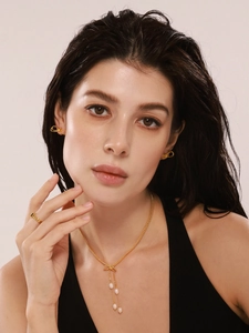 Gros plan sur le collier à nœud en perles d'eau douce doré et les boucles d'oreilles assorties