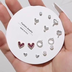 Detailed view of mixed heart and pearl stud earring set on circular fashion card