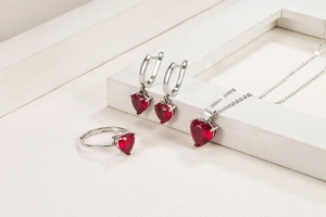 Macro detail of silver heart jewelry set with ruby-colored zircon necklace and earrings