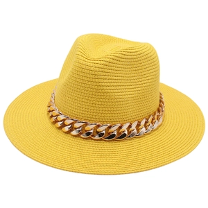 Texture détaillée d'un chapeau de paille jaune avec une grosse chaîne en métal doré