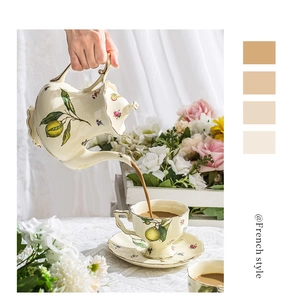 Detailed pour of tea from a French floral ceramic teapot with gold trim and lemon patterns