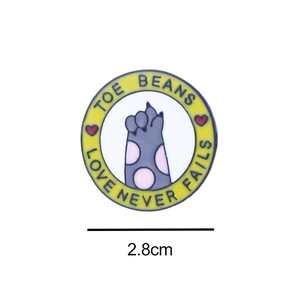 Detail of 2.8cm round enamel pin with cat paw design and Toe Beans text engraving
