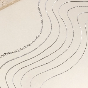 Various S925 sterling silver chain styles including heart and snake links on stone